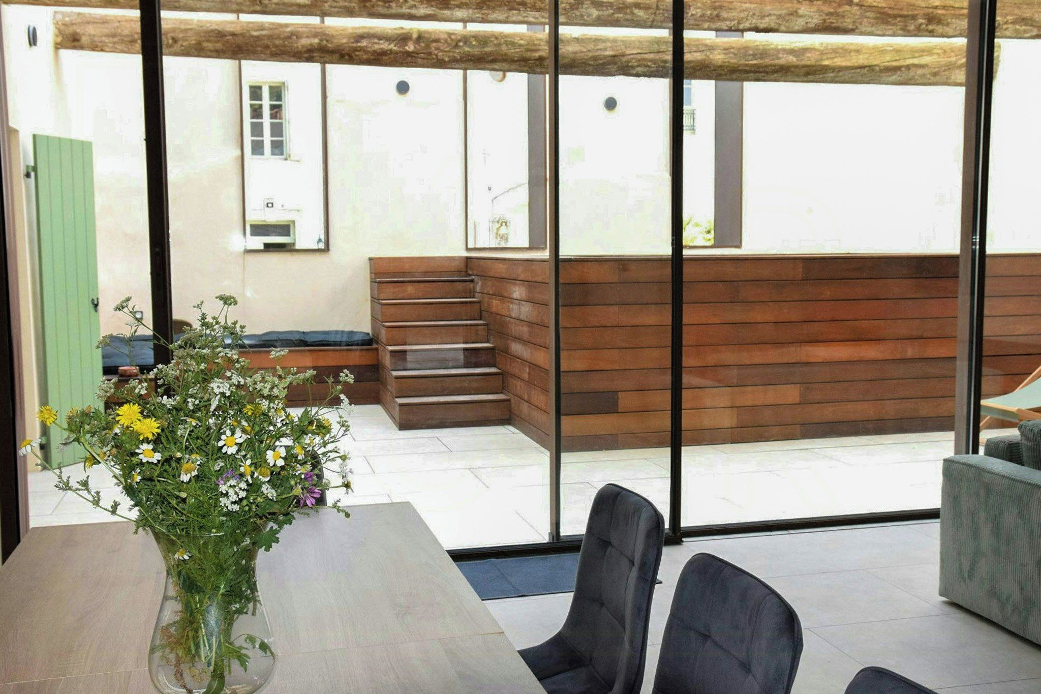 Un interior moderno con un banco de madera, una mesa de comedor con sillas y un ventanal con vistas al exterior.