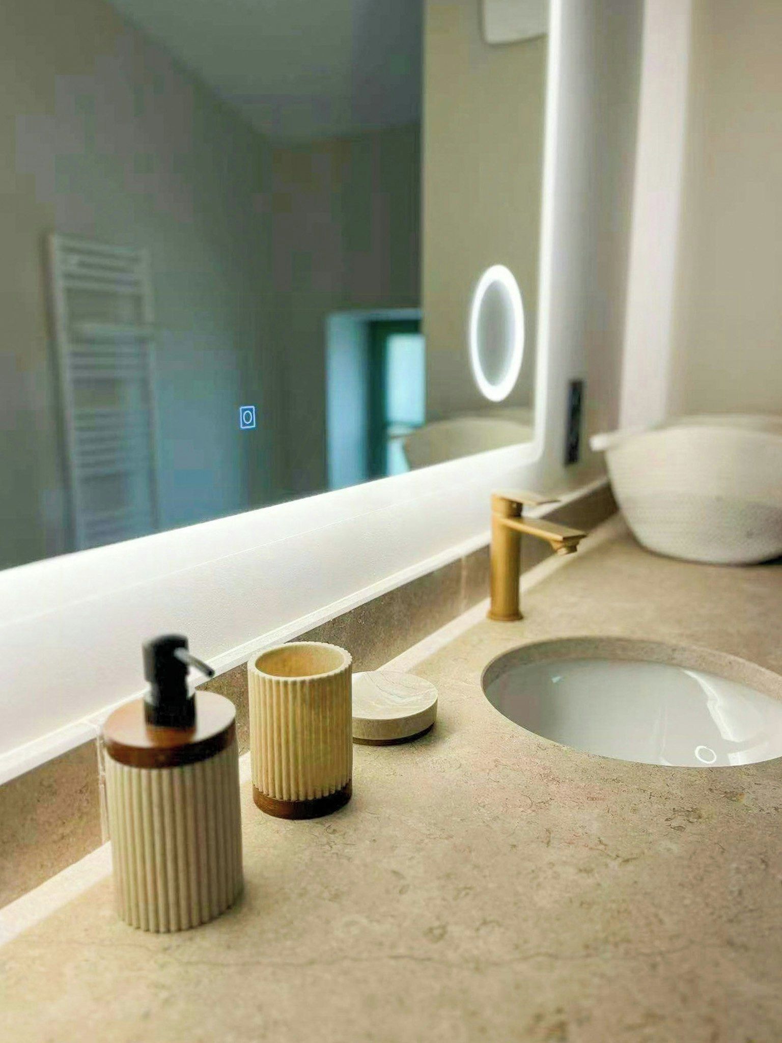 A bathroom vanity with a mirror, a sink, and a soap dispenser.
