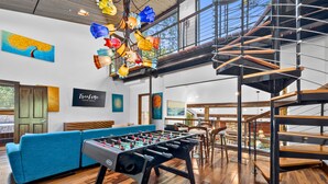 Un intérieur moderne avec un baby-foot, un canapé bleu et un escalier.