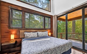 Ein Schlafzimmer mit einem großen Bett, einem Holzkopfteil und mehreren Fenstern.