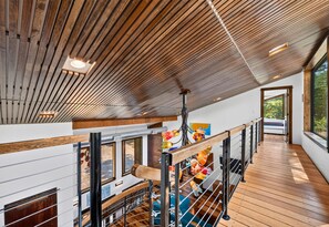 Espaçoso interior com teto alto, vigas de madeira e mezanino com guarda-corpo.