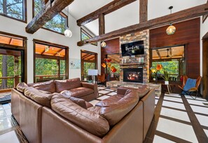 A spacious living area with a fireplace, leather sofas, and large windows. - Games | Gallery Vibes | Hot Tub | Sleeps 14 (Broken Bow)