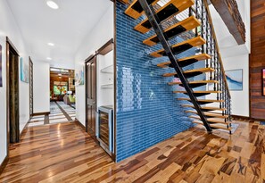 Ein modernes Interieur mit einer Holztreppe, einer blauen Fliesenwand und Holzboden.