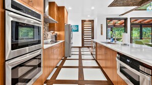 Une cuisine moderne dotée d’appareils électroménagers en acier inoxydable, de meubles de rangement en bois et d’un carrelage au motif à carreaux.