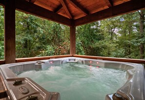 Ein Whirlpool mit Holzdach und Blick auf einen Wald.