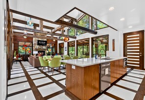 A modern kitchen with a central island, large windows, and a fireplace. - Games | Gallery Vibes | Hot Tub | Sleeps 14 (Broken Bow)