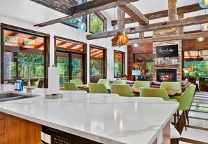 A modern kitchen with a large island, green chairs, and a fireplace. - Games | Gallery Vibes | Hot Tub | Sleeps 14 (Broken Bow)