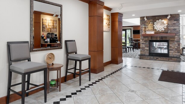 A hotel lobby with a fireplace, a mirror, and two bar stools. - Accessible King Studio w/ Roll Shower & Breakfast (Harrisburg)