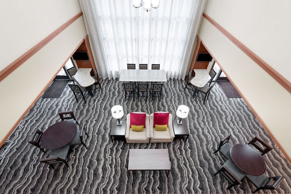 A hotel lobby with a central seating area, a staircase, and a view of the upper floor.