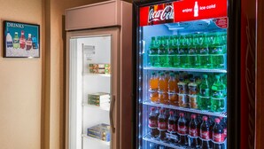 A vending machine with various beverages and a refrigerator with snacks. - Accessible King Studio w/ Roll Shower & Breakfast (Harrisburg)