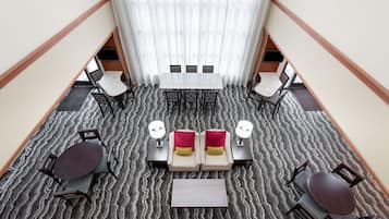 Un hall d’hôtel doté d’un espace salon central, d’un escalier et d’une vue sur l’étage supérieur.