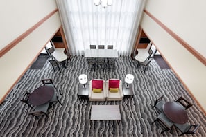 A hotel lobby with a central seating area, a staircase, and a view of the upper floor.