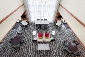 En hotellobby med en central sittgrupp, en trappa och utsikt över våningen ovanför.
