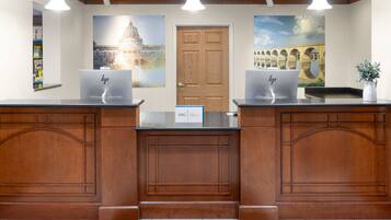 A reception desk with two HP computers, a door, and a wall with a large painting.