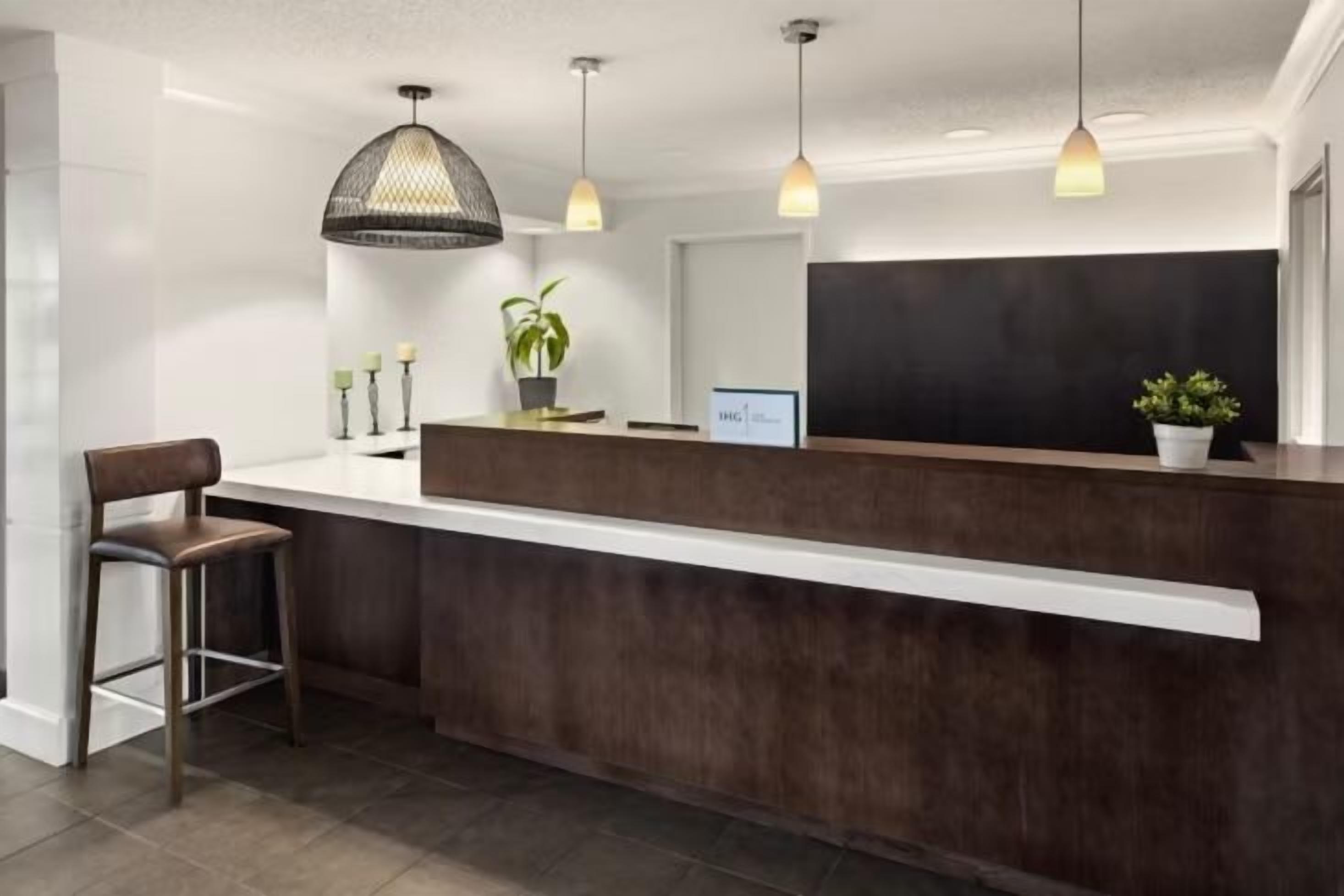 A reception desk with a dark wood finish, pendant lighting, and a potted plant.