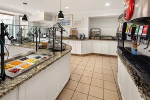 A buffet area with a variety of food options, a coffee machine, and a seating area with a counter.