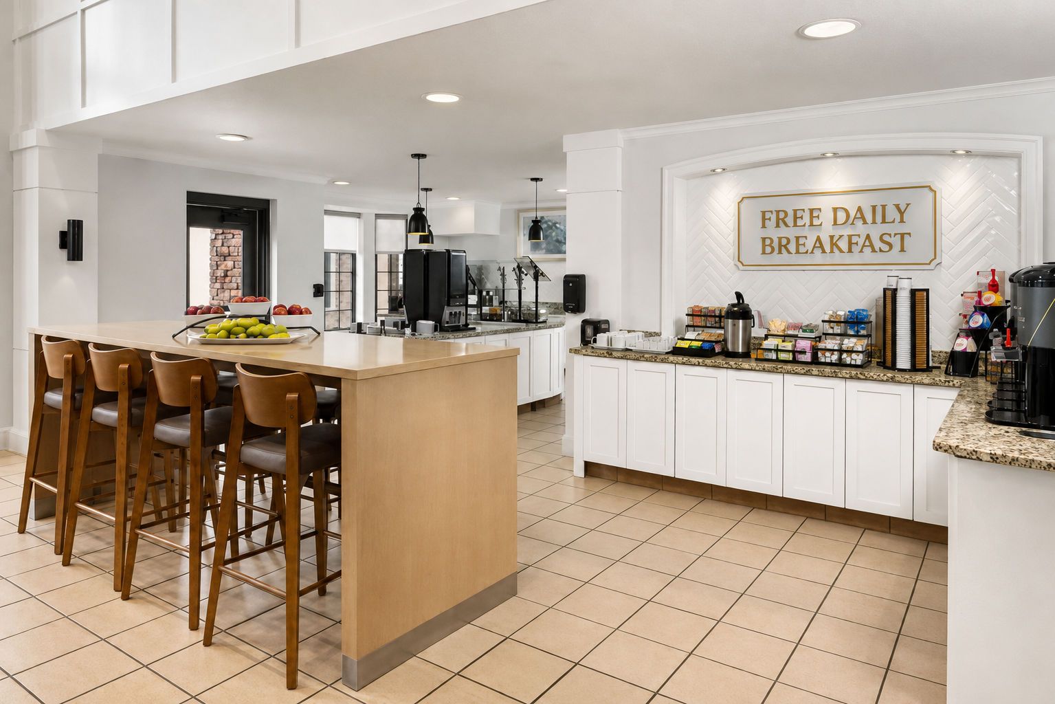 A modern kitchen with a central island, bar stools, and a sign indicating free daily breakfast.