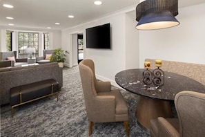 Una habitación de hotel moderna con un conjunto de sofá, una mesa redonda con velas y un televisor de pantalla plana montado en la pared.