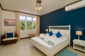 Une chambre à coucher avec un grand lit, une chaise, une table de chevet et une fenêtre avec des rideaux.