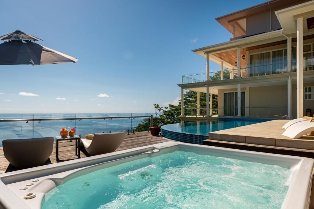 Una vasca idromassaggio con vista sull'oceano, una piscina e un edificio con un balcone.