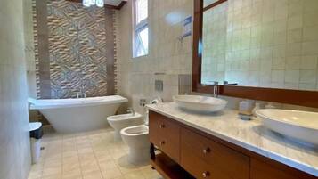 A modern bathroom with a freestanding bathtub, a large vanity with a mirror, and a toilet.