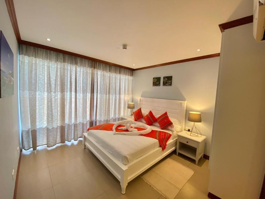 Ein Hotelzimmer mit einem großen Bett, zwei Nachttischen und einem Fenster mit Vorhängen.