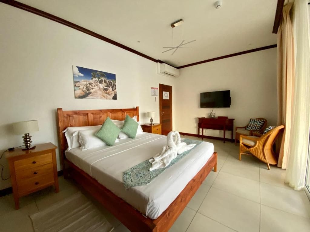 Una habitación de hotel con una cama, televisor, escritorio y una silla.