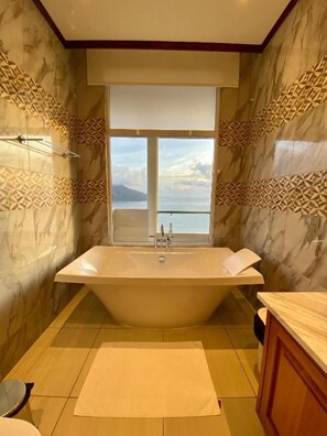 Une salle de bain avec une baignoire sur pieds, une fenêtre offrant une belle vue et des murs décorés de motifs.