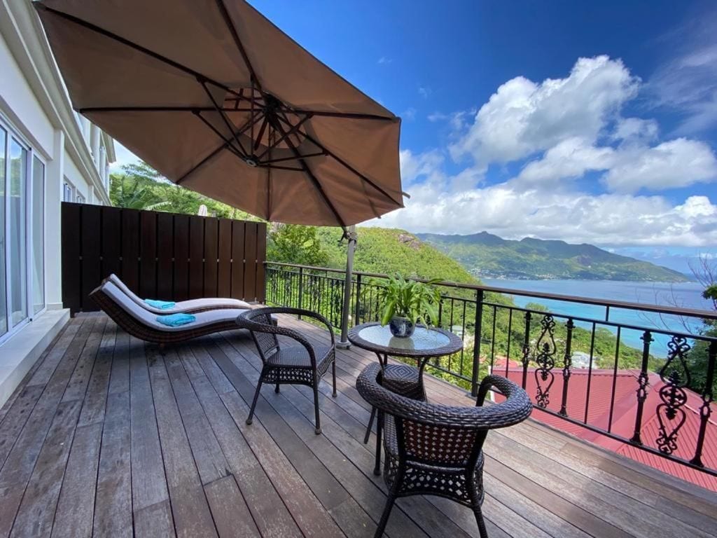 A wooden deck with a lounge chair, a small table, and an umbrella.