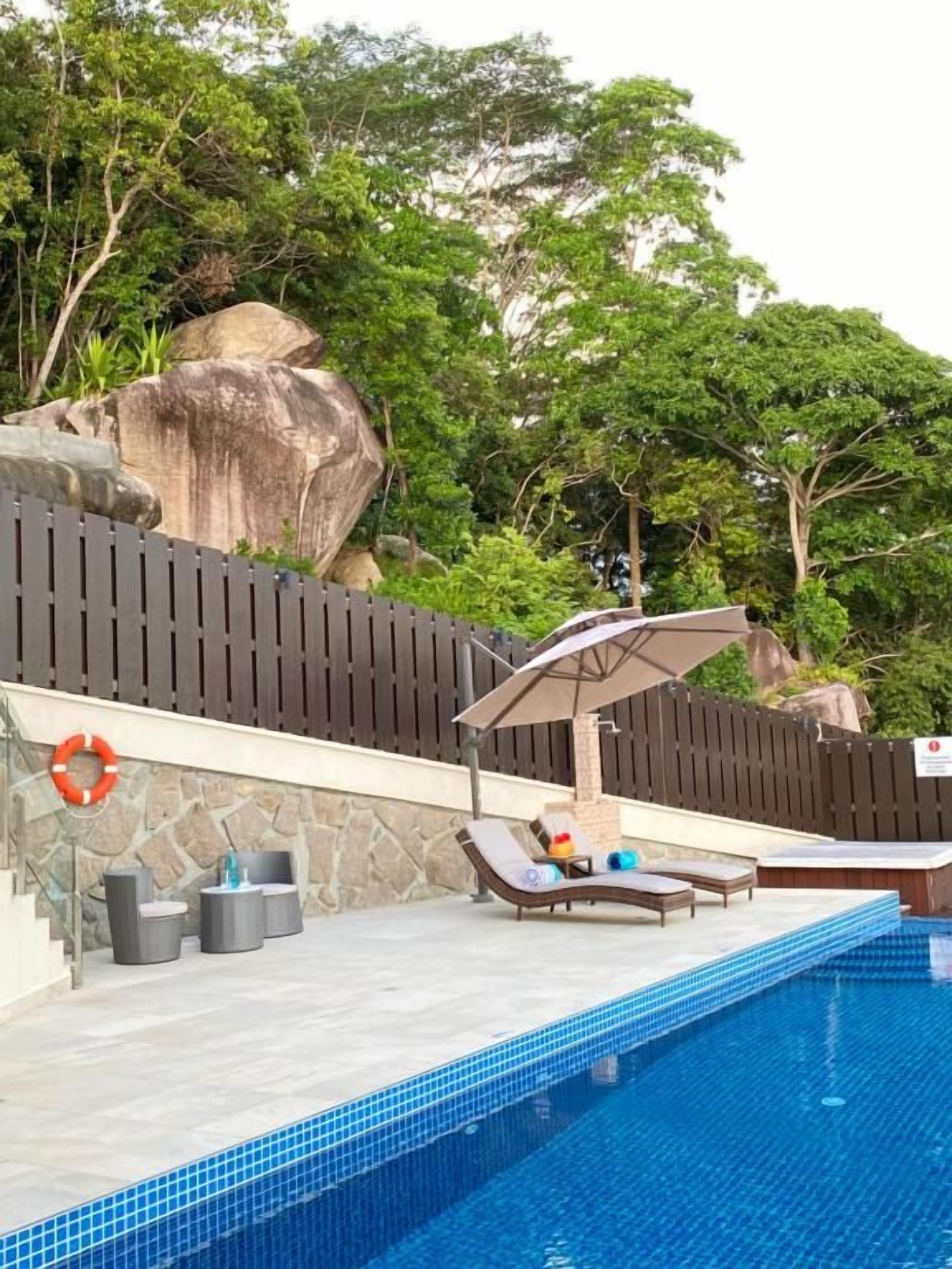 A swimming pool with lounge chairs and a shaded area.