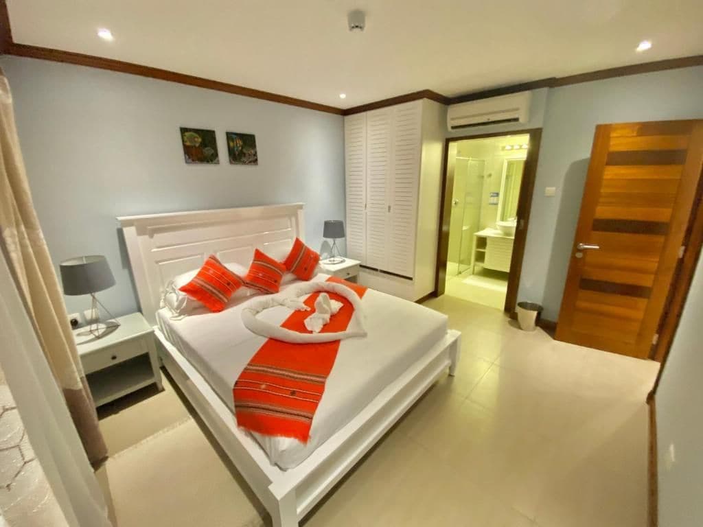 A hotel room with a bed, bedside table, and a bathroom visible through an open door.