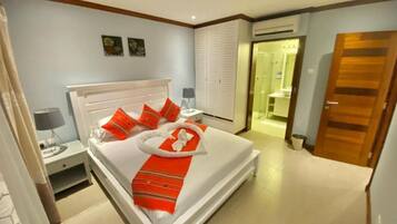 A hotel room with a bed, bedside table, and a bathroom visible through an open door.