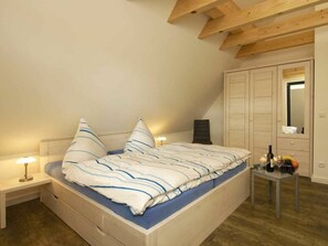Ein Schlafzimmer mit Bett, Nachttischen, einem Kleiderschrank und einem Spiegel.