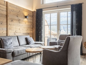 A modern living room with a grey sofa, a round wooden coffee table, and a grey armchair. - Superior Holiday Home # 5A With Sauna (Uttendorf)