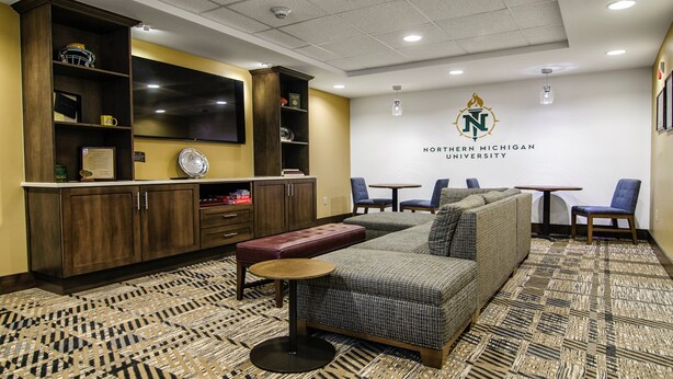 A university lounge with a sofa, chairs, a small table, and a bookshelf. - Accessible 2BR Suite w/ Kitchen + Daily Breakfast (Marquette)