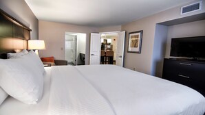 Een hotelkamer met een groot bed, een televisie, een bureau met stoel, en een badkamer die door een open deur zichtbaar is.
