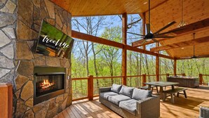 Une terrasse en bois avec une cheminée en pierre, un canapé et une table.