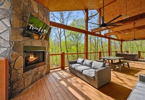 Eine Holterrasse mit Kamin aus Stein, einer Couch und einem Tisch.