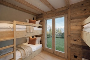 Habitación con literas de madera y vistas a montañas a través de amplios ventanales.