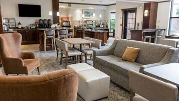A hotel lobby with a seating area, a bar, and a television.