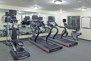 A fitness center with treadmills, elliptical machines, and a mirrored wall.