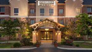 Een Staybridge Suites hotel met een gevel van baksteen, een centrale ingang met een boog en een goed verlichte gevel.