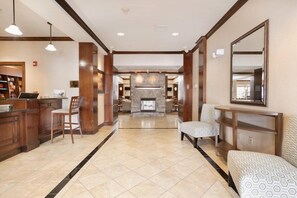 Un hall d’hôtel doté d’une cheminée, d’un espace salon et d’un comptoir d’accueil.