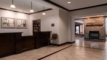 A reception area with a counter, a chair, a stone fireplace, and framed artwork on the wall.