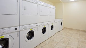 A laundry room with multiple stacked washing machines and dryers.