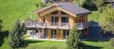 Une cabane en bois à deux étages, dotée d’un balcon et entourée d’un paysage verdoyant.