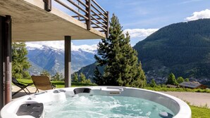 A hot tub with a mountain view, a wooden deck, and a chair. - Chalet Aramis - Four Bedroom Chalet, Sleeps 8 (Riddes)