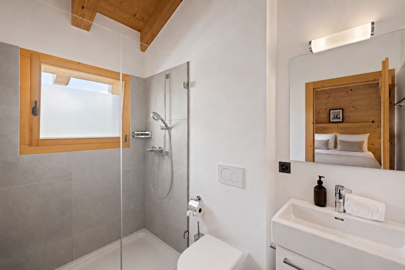 A modern bathroom with a glass shower enclosure, a white sink with a mirror, and a wooden ceiling.