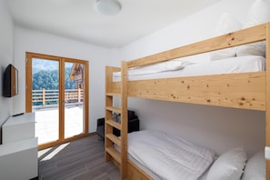 Une chambre avec un lit superposé, un bureau et un téléviseur.