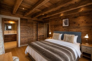 A wooden-paneled bedroom with a bed, bedside lamps, and a mirror. - Chalet Big Bear - Five Bedroom Chalet, Sleeps 10 (Riddes)